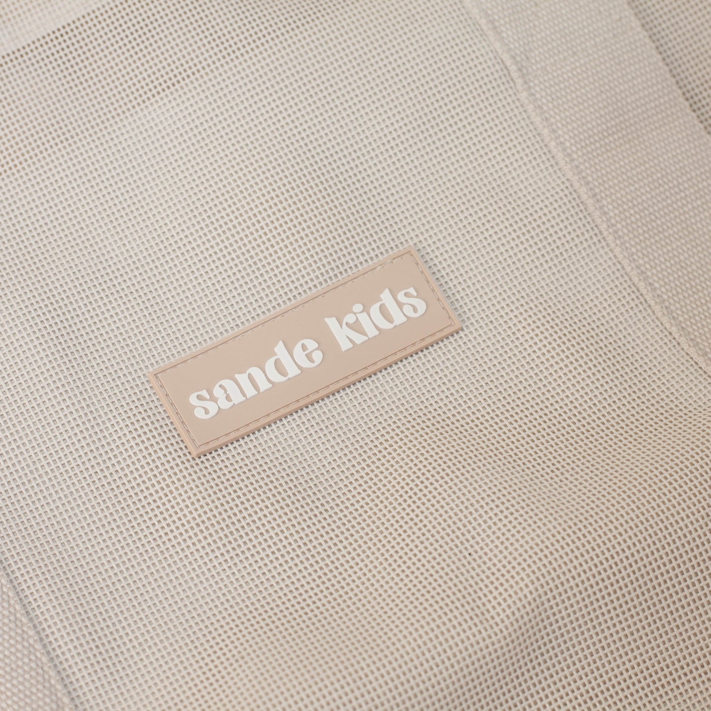 Sande Kids Beach Hauler™ - Close up on neutral mesh fabric and silicone brand label.