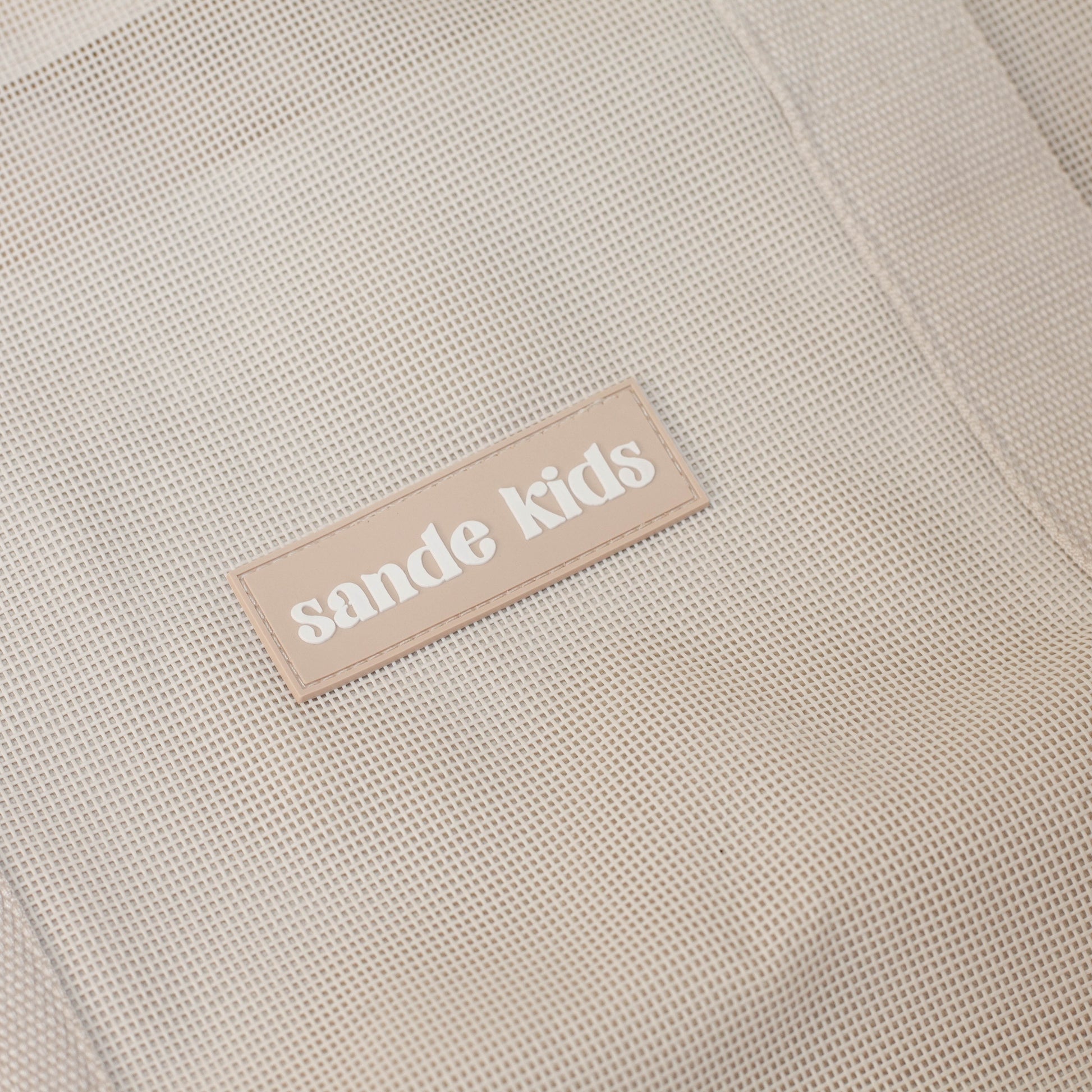 Sande Kids Beach Hauler™ - Close up on neutral mesh fabric and silicone brand label.